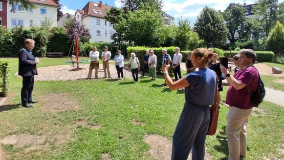 Auf dem Bild sieht man Bürgermeister Frank Hasenberg und eine Gruppe von Menschen, die im Halbkreis steht.