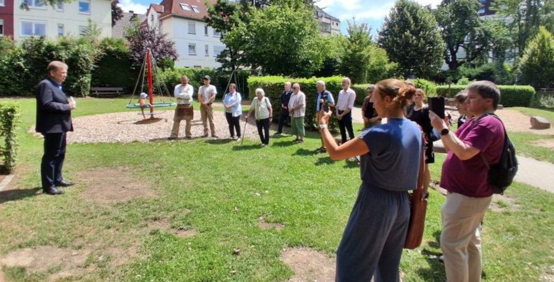 Auf dem Bild sieht man Bürgermeister Frank Hasenberg und eine Gruppe von Menschen, die im Halbkreis steht.