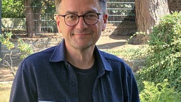 Auf dem Bild sieht man Thomas Kutschaty, der in die Kamera schaut und ein Faltblatt in der Hand hat.